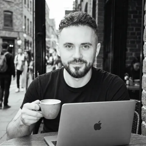 Vlad, osnivač xelra digital, za stolom sa laptopom i šoljom kafe